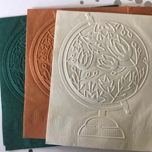 May include: Three paper napkins with an embossed design of a globe with stylized flowers and leaves. The napkins are in green, orange, and white.