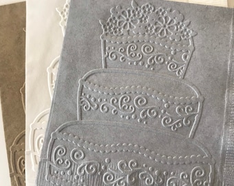 May include: Three paper napkins with an embossed design of a three-tiered wedding cake. The napkins are in shades of brown, white, and gray.