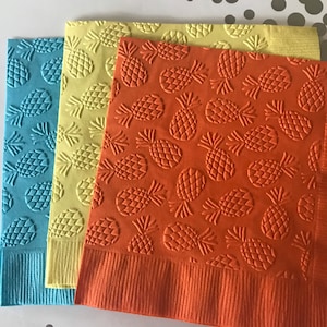 May include: Three paper napkins with a pineapple pattern. The napkins are in shades of blue, yellow, and orange.