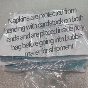 May include: A stack of napkins wrapped in clear plastic and tied with a blue and white ribbon. The napkins are protected from bending with cardstock on both ends and are placed inside a poly bag before going into a bubble mailer for shipment.