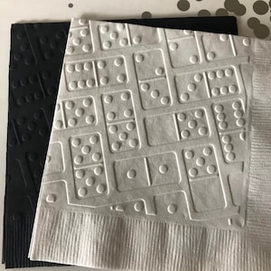 May include: Two paper napkins with a domino pattern. One napkin is black and the other is white.