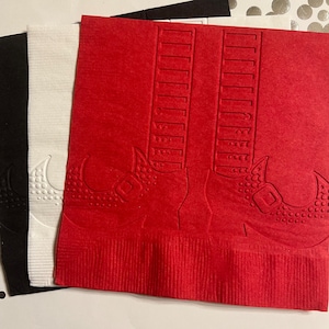 May include: Red paper napkins with a white embossed design of a pair of witch's boots with buckles.