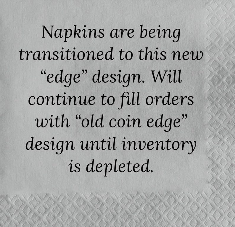 May include: A close-up of a white napkin with black text that reads: "Napkins are being transitioned to this new "edge" design. Will continue to fill orders with "old coin edge" design until inventory is depleted."