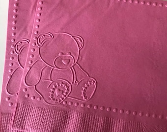 Könnte beinhalten: Rosa Papier-Servietten mit einem weißen, geprägten Teddybär-Motiv. Die Servietten haben einen gepunkteten Rand.