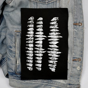 May include: Black fabric patch with a white graphic design of three rows of jagged, tooth-like shapes.