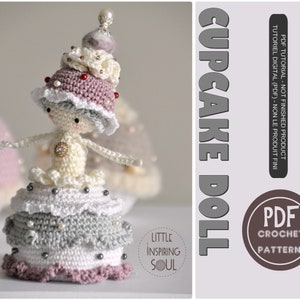 Peut inclure: Un patron de poupée cupcake au crochet. La poupée porte un chapeau de cupcake rose et blanc avec une perle sur le dessus. La poupée porte une robe blanche avec une jupe de cupcake grise et blanche. La poupée est assise sur une base de cupcake grise et blanche. Le patron est disponible en téléchargement numérique.
