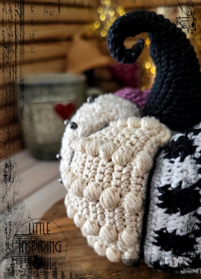 May include: A crocheted amigurumi toy with a white, black and purple body. The toy has a large, curled black horn and a textured white body.