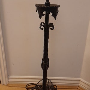 May include: A black wrought iron table lamp with a twisted stem and ornate details. The lamp has a gold-coloured socket and a simple round base.