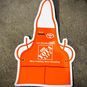 May include: Orange and white apron with a Toyota logo and the text "Hi, I'm Toyota. I put offroading FIRST. THE YOTA LIFE. More modding. More offroading."