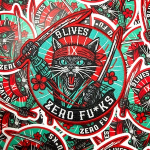 May include: A collection of stickers featuring a black cat with a red headband, holding two swords. The cat has green eyes and is surrounded by the text "9 LIVES" and "ZERO FU*KS". Red and black accents on a teal background.