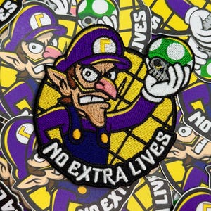 May include: Embroidered patch featuring a cartoon character in purple and yellow, holding a green mushroom with a skull design. The patch has the text "NO EXTRA LIVES" in white. The background is filled with similar stickers.