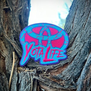 May include: A blue and pink embroidered patch with a cracked design and the text "YOTA LIFE".