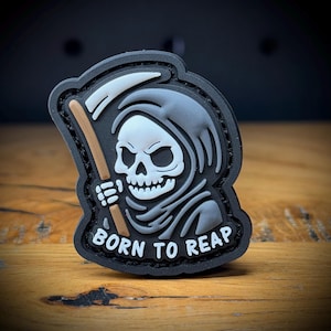 May include: A black and gray patch featuring a grim reaper with a scythe and the text "BORN TO REAP" in white. The reaper has a skull face and is wearing a hooded cloak. The patch is on a wooden surface.