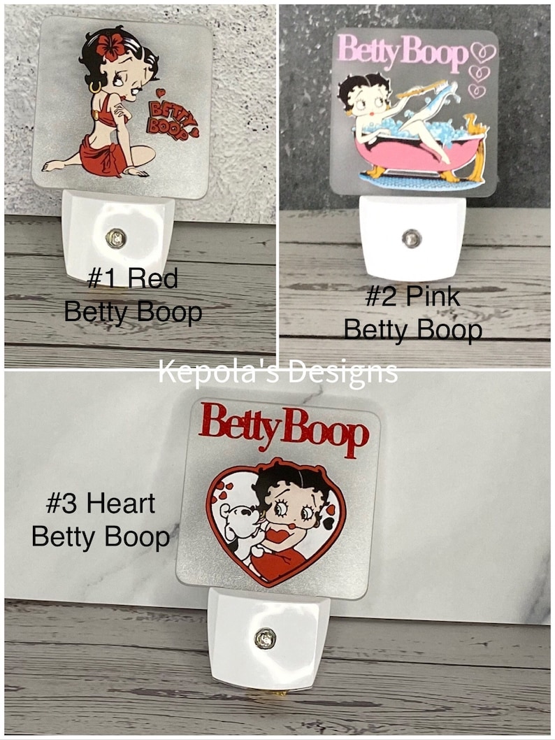 May include: Three Betty Boop night lights. The first features Betty in red, the second in a pink bathtub, and the third with a heart design. Each night light has a white base and a decorative image.