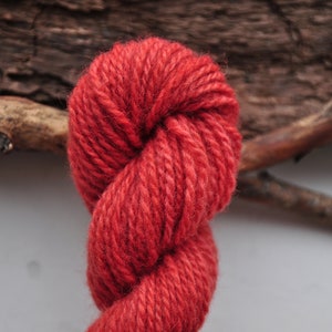 May include: A skein of red yarn, twisted and looped, against a rustic wooden background.