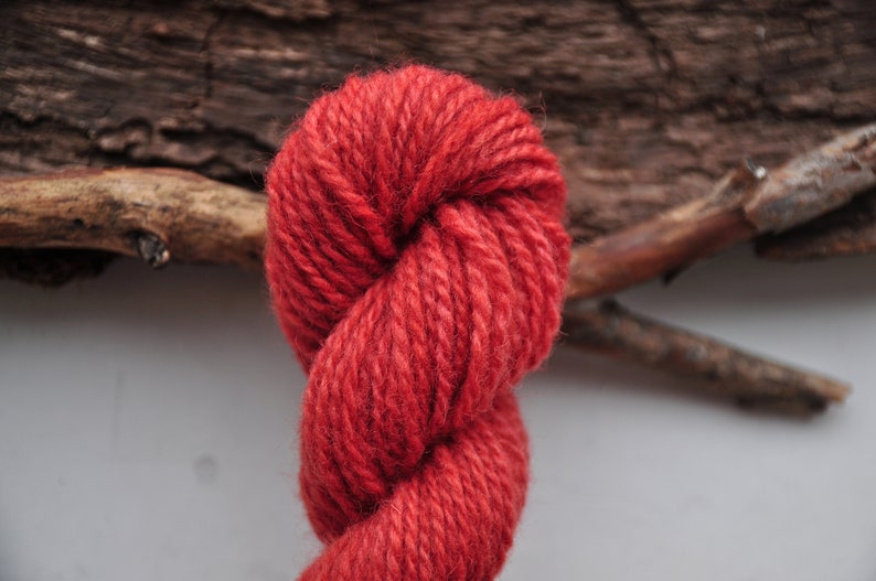 May include: A skein of red yarn, twisted and looped, against a rustic wooden background.
