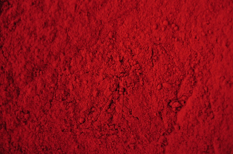 May include: Close-up of a vibrant red powder, possibly paprika or chili powder, with a textured surface.