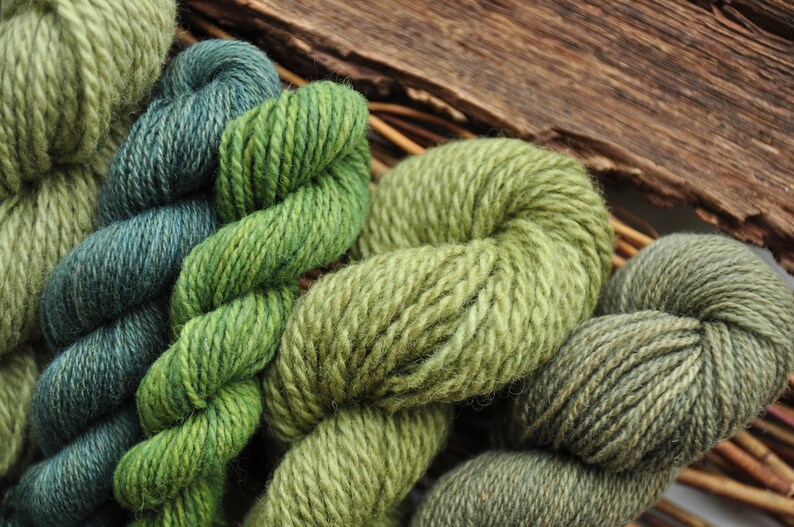 May include: Close-up of five skeins of yarn in various shades of green. The yarn is soft and fluffy, and the colours are rich and vibrant.
