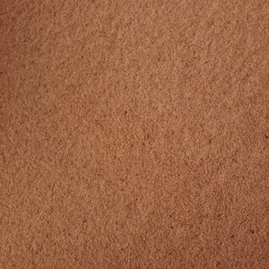 Puede incluir: Primer plano de una superficie texturizada marrón. La superficie tiene una textura rugosa y granulada.