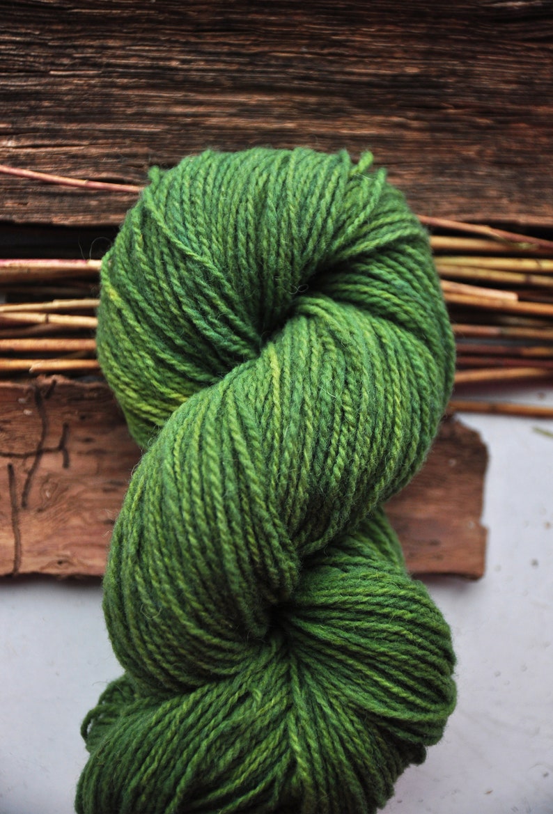May include: A skein of green yarn with a variegated colour pattern. The yarn is twisted into a figure of eight shape.