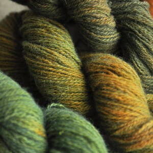 May include: Close-up of yarn in shades of green and brown. The yarn is soft and fluffy, and it is perfect for knitting or crocheting.