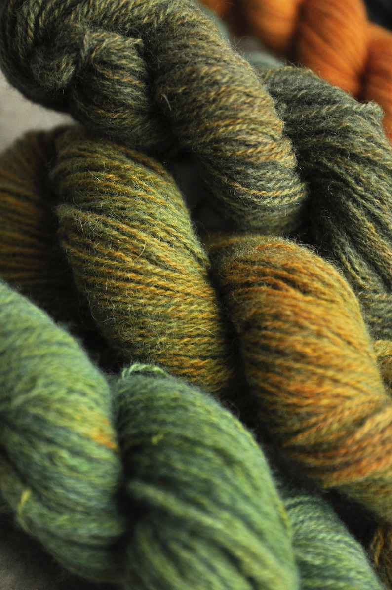 May include: Close-up of yarn in shades of green and brown. The yarn is soft and fluffy, and it is perfect for knitting or crocheting.