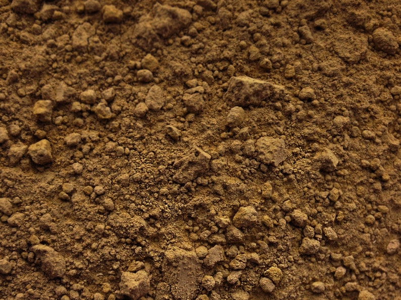 May include: Close-up of a brown, grainy powder. The powder has a rough texture and is made up of small, irregular particles.