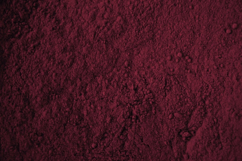 May include: Close-up of a deep red powder, possibly cocoa powder or beetroot powder, with a fine, grainy texture.