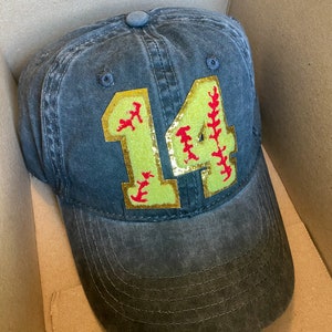May include: A black baseball cap with a yellow and red softball number 14 patch.