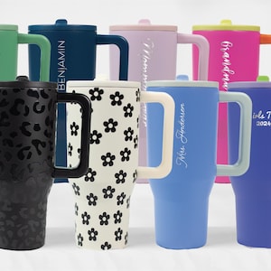 May include: A collection of 10 personalized travel mugs with various colors and designs. The mugs feature different names, phrases, and patterns, including "C.M.D.", "Benjamin", "Girls Trip 2024", and a floral pattern.