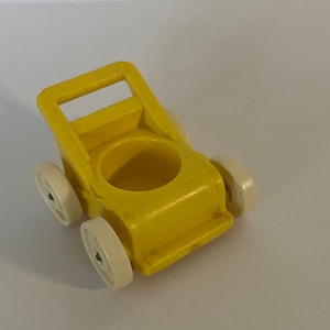 Pode incluir: Um carrinho de brinquedo de plástico amarelo com rodas brancas. O carrinho tem uma alça e um assento.