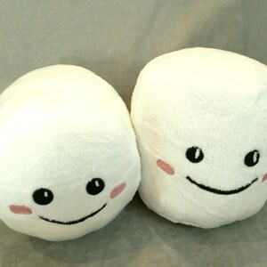May include: Two white plush marshmallow toys with embroidered smiling faces and pink cheeks.