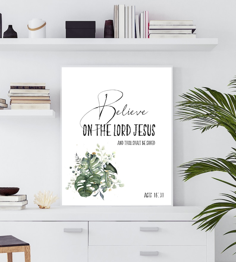 May include: A white printable art print with a green watercolor floral design. The print features the text "Believe on the Lord Jesus and thou shalt be saved" with the scripture reference "Acts 16:31".