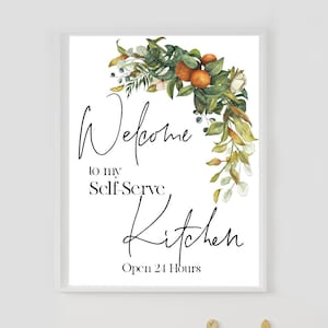 May include: A white framed sign with the text "Welcome to my Self-Serve Kitchen" in black script, decorated with a watercolour illustration of green leaves, orange fruits, and white flowers. The words "Open 24 Hours" are at the bottom.