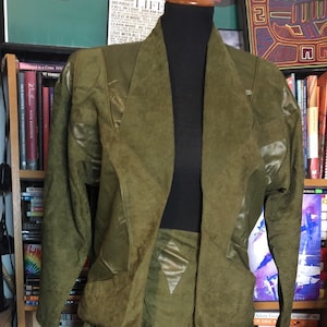 May include: A green suede jacket and skirt set. The jacket has a shawl collar and the skirt has a gathered waist.