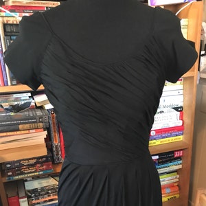 May include: A black short-sleeved dress with a scoop neck and a pleated skirt.