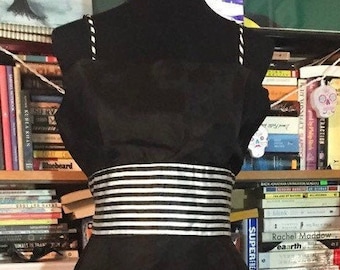 May include: A black and white striped dress with a black bodice and a white and black striped skirt. The bodice has a black and white striped band around the waist.