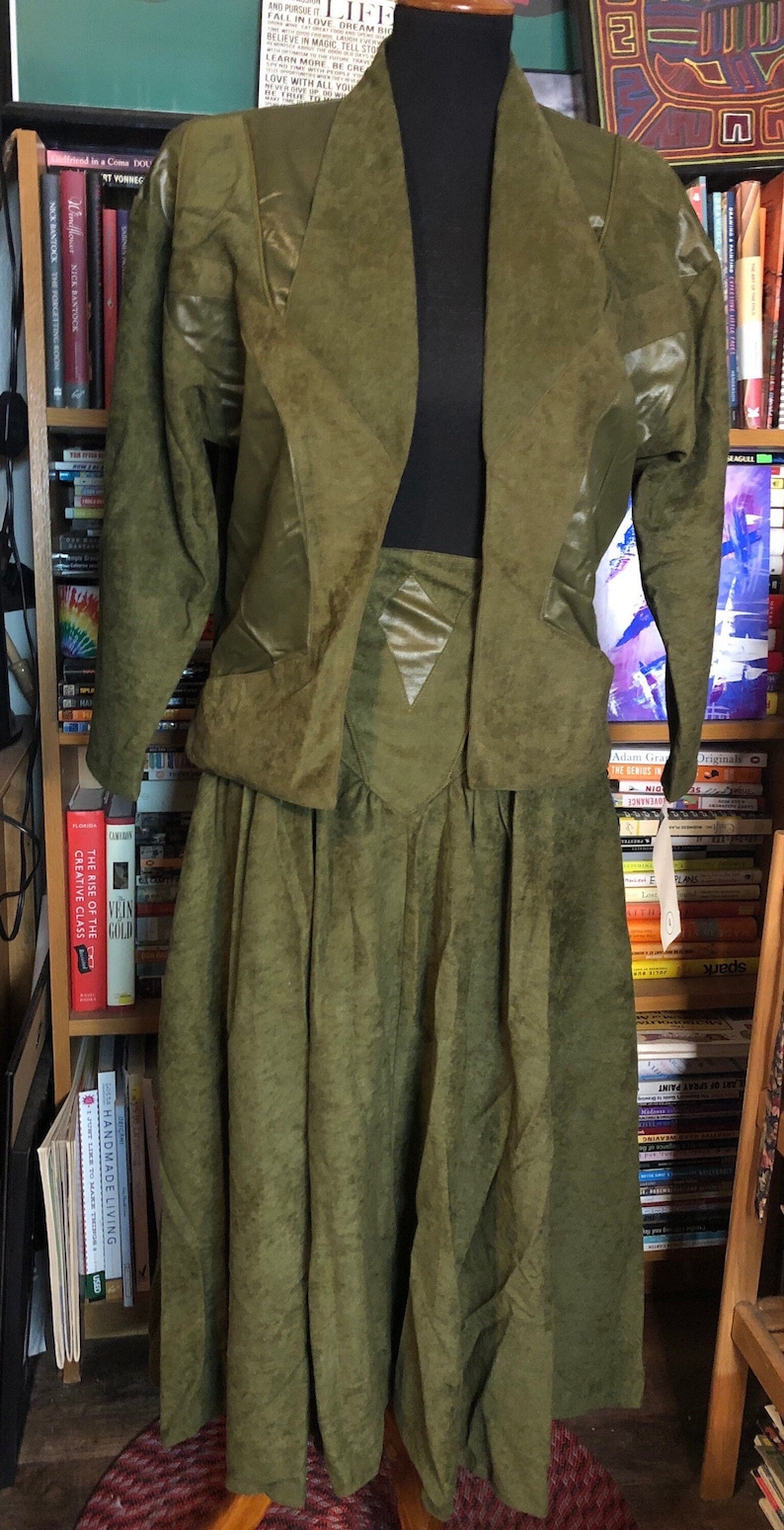 May include: A green suede jacket and skirt set. The jacket has a shawl collar and the skirt has a gathered waist.