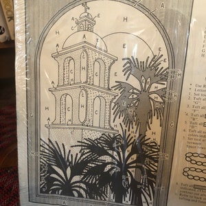 May include: A black and white line drawing of a California mission with a bell tower, palm trees, and instructions for rug hooking. The instructions include letters and numbers to indicate the order of the steps. The text on the page reads "35-589 California Mission" and "RC Rug Crafters".