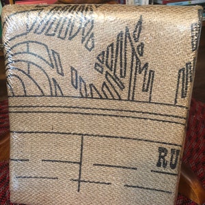 May include: A brown burlap book cover with black geometric designs and the word "RU" printed on the bottom right corner.