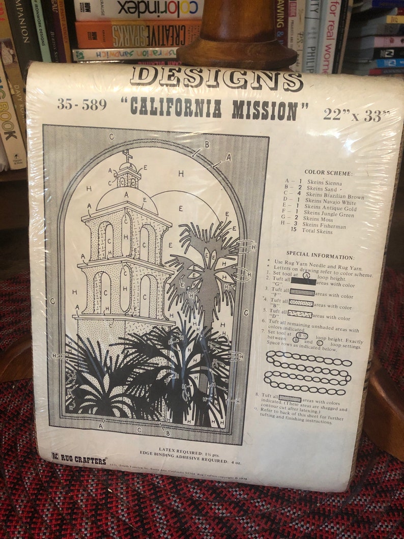 May include: A black and white rug hooking pattern for a California Mission design. The pattern includes a detailed drawing of a mission building with palm trees and a color key with 15 different colors. The pattern is labeled "35-589 "California Mission" 22" x 33"