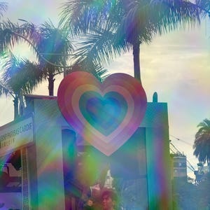 May include: A large rainbow heart-shaped sign with the text "BNP PARIBAS CARDIF" on a sign behind it. The sign is in front of a palm tree and a blurry background.