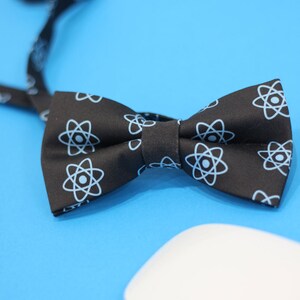 May include: Black bow tie with a white atom pattern.