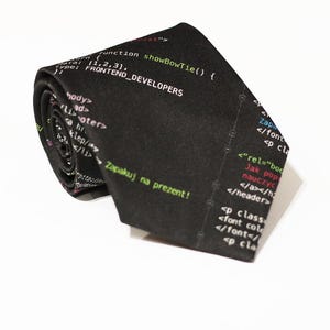 Peut inclure: Une cravate noire avec un motif de code informatique imprimé dessus. Le code comprend le texte "FRONTEND DEVELOPERS" et "Zapakuj na prezent!" qui se traduit par "Emballez-le en cadeau!" en polonais.