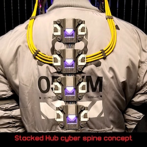 Puede incluir: Un concepto de columna vertebral cibern&eacute;tica futurista con un dise&ntilde;o de concentrador apilado. La columna vertebral est&aacute; hecha de m&uacute;ltiples m&oacute;dulos grises y negros con luces moradas brillantes. La columna vertebral est&aacute; unida a una persona que lleva una chaqueta gris con correas amarillas.
