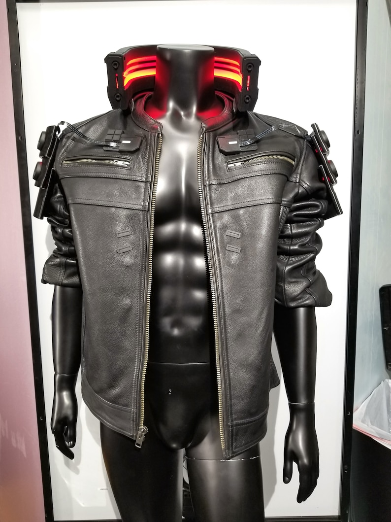 May include: A black leather jacket with a zipper closure and a red light-up collar. The jacket has a futuristic design with details on the shoulders and arms.