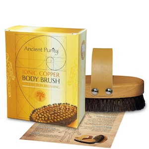 Pode incluir: Um conjunto de escova corporal com cabo de madeira e caixa. A caixa é amarela com as palavras "Ancient Purity" e "Ionic Copper Body Brush" impressas. A escova tem cerdas escuras e uma tira de couro castanho claro.
