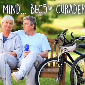 May include: An older couple sits on a park bench with bicycles nearby. The woman wears a gray sweatsuit, and the man wears a light blue shirt. The text "PEACE OF MIND... BEC5&reg; CURADERM CREAM" is at the top of the image.