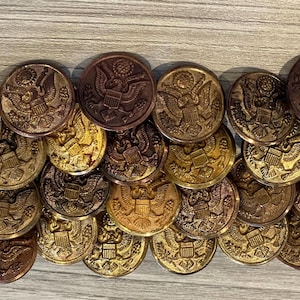 May include: A collection of gold and bronze buttons featuring the United States seal. The buttons are arranged in a semi-circle pattern.