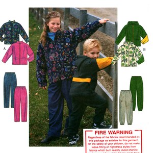 May include: Two children wearing matching jackets and trousers. The girl is wearing a floral print jacket and trousers, while the boy is wearing a yellow and black jacket and black trousers. The jackets have a zip closure and a stand-up collar. The trousers have an elastic waistband and a drawstring. The children are standing in front of a wooden fence. The image includes a warning about fire safety.